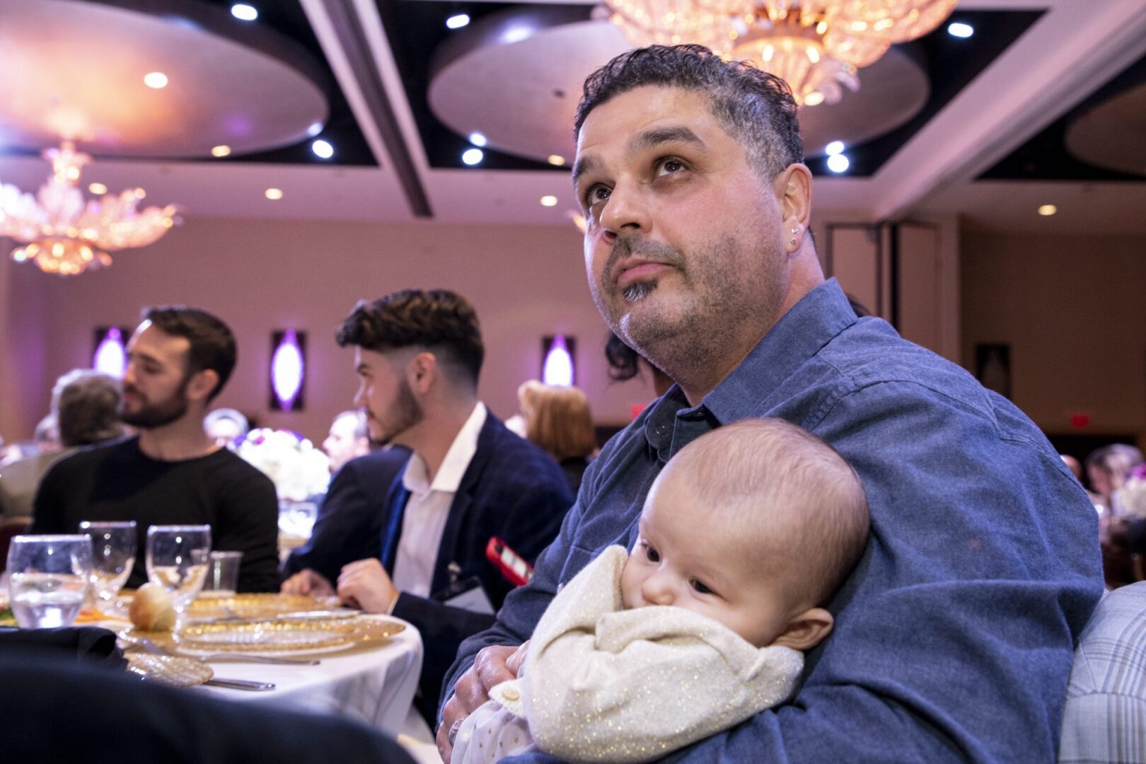 A man holding a baby at a banquet.
