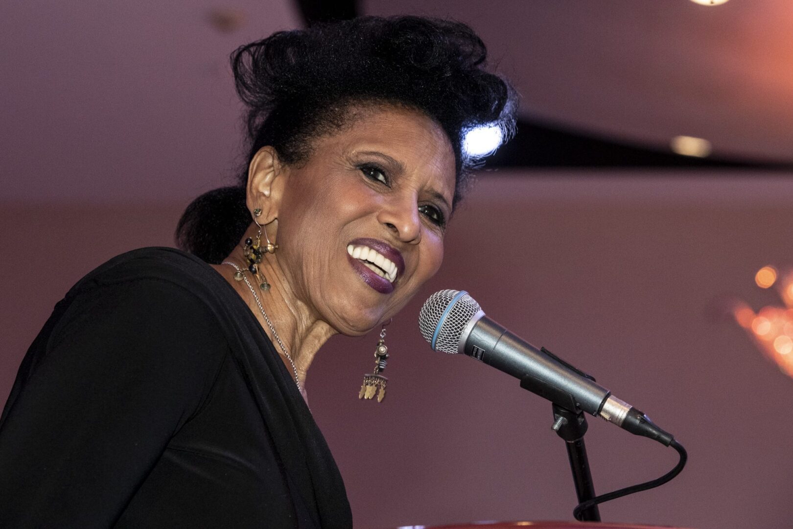 A black woman smiling into a microphone.