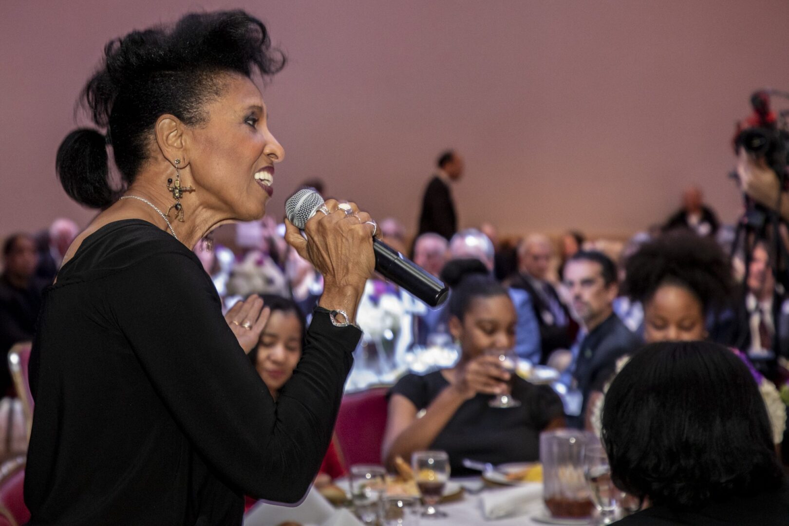 A woman is speaking into a microphone at a banquet.