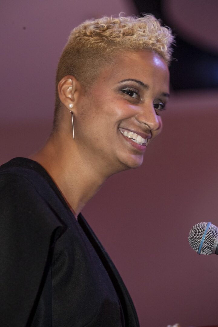 A woman smiling while holding a microphone.
