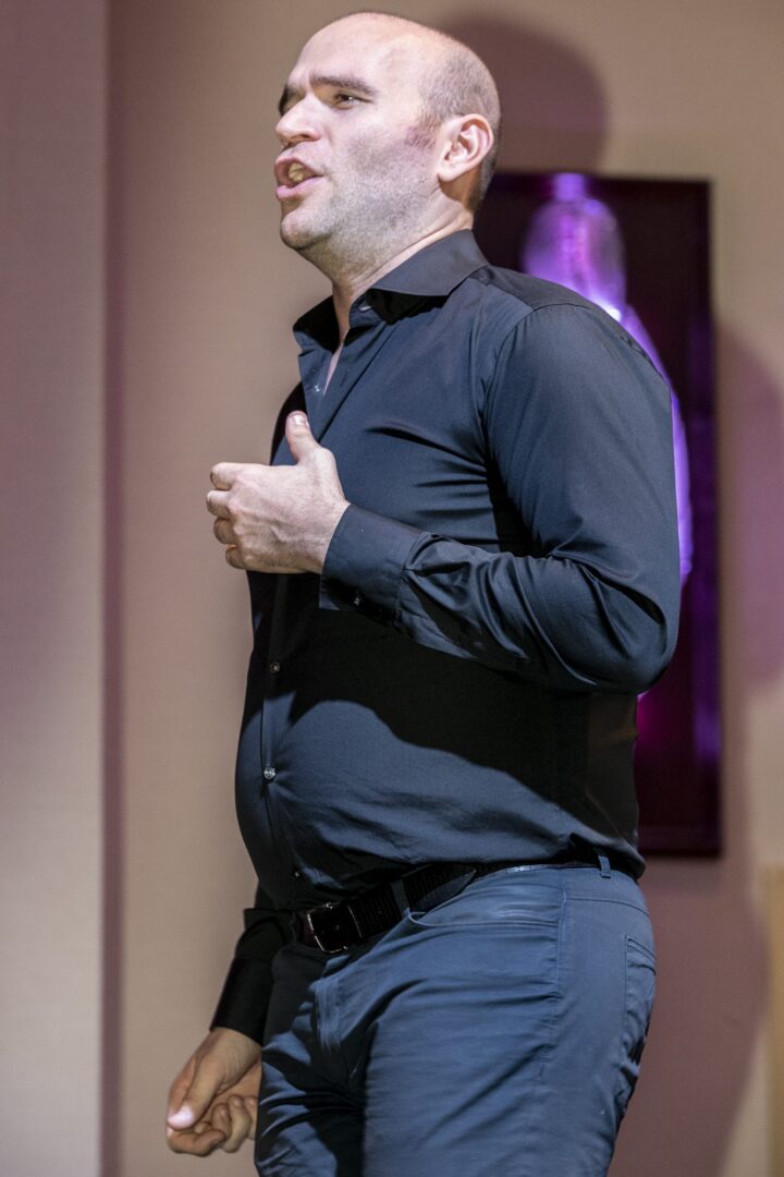 A bald man in a black shirt standing on stage.