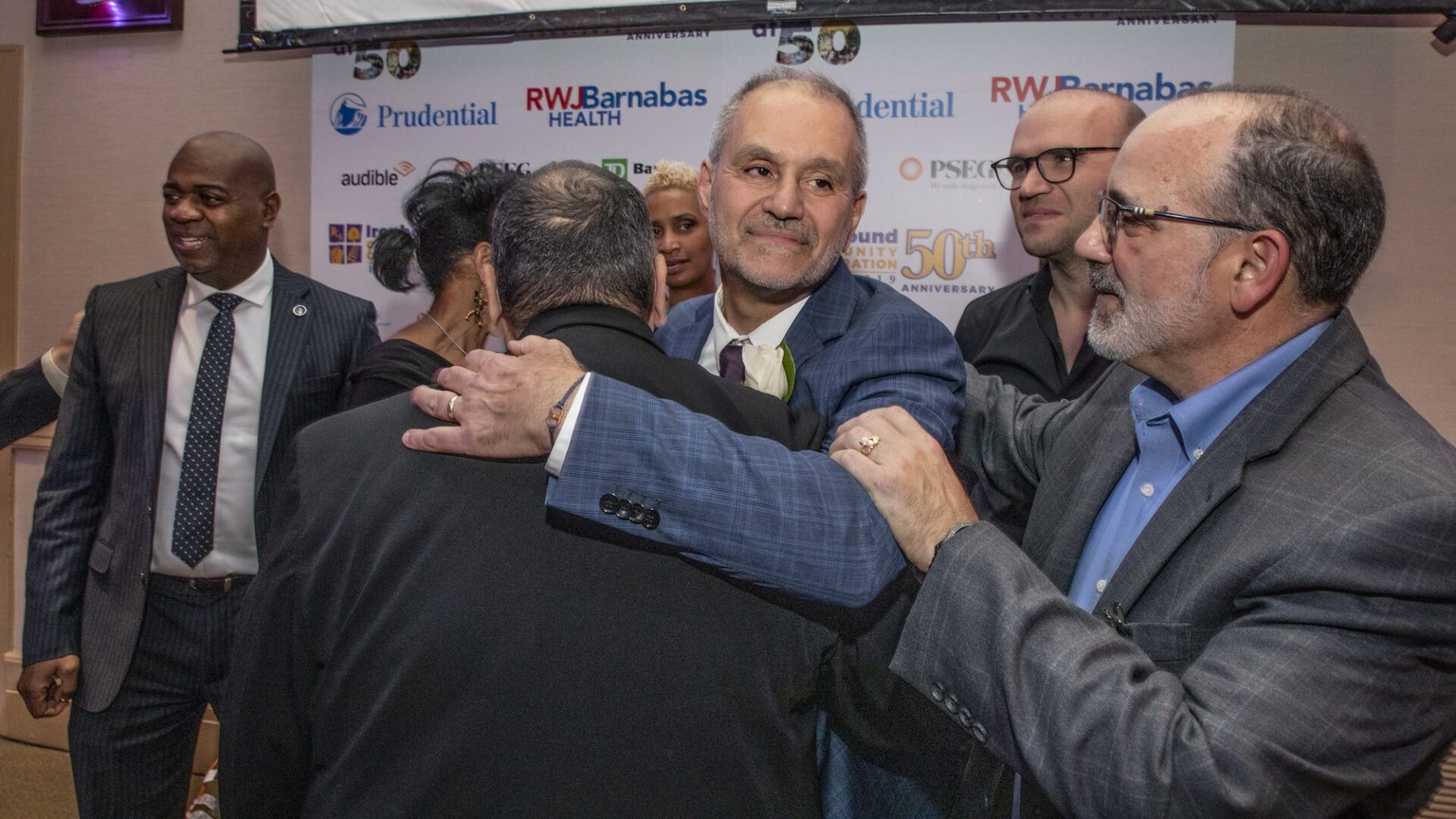 A group of men hugging each other at an event.