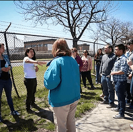 People talking in front of a fence.