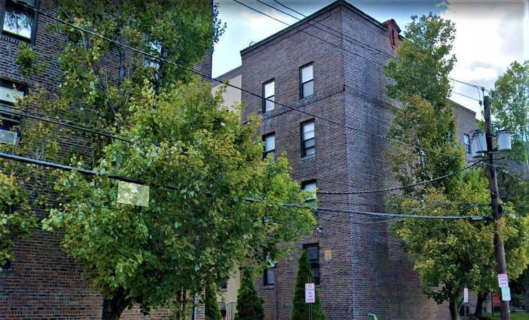 A brick apartment building with trees in front.