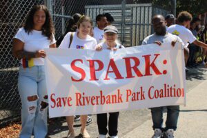 Group holding Save Riverbank Park Coalition banner.